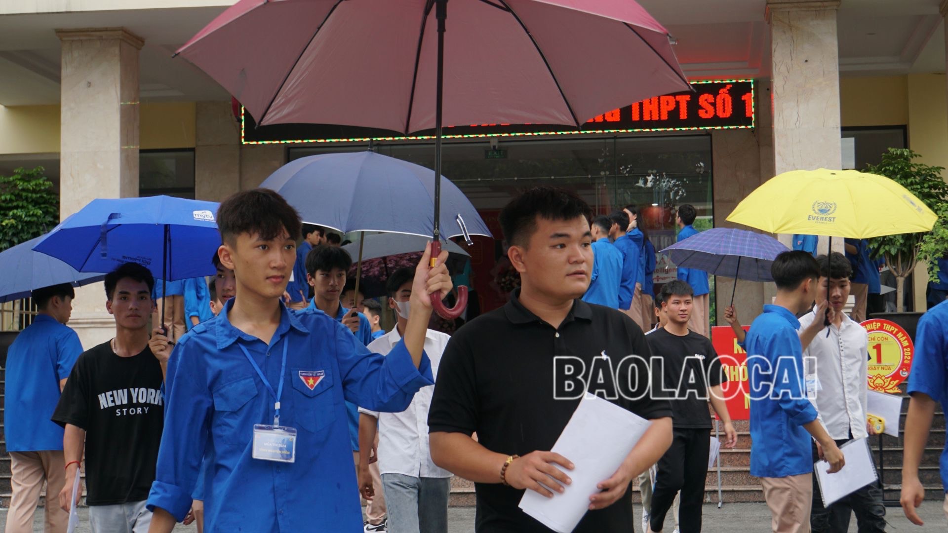Lực lượng đoàn viên, thanh niên tình nguyện hỗ trợ che ô cho thí sinh tại điểm thi Trường THPT số 1 thành phố Lào Cai.