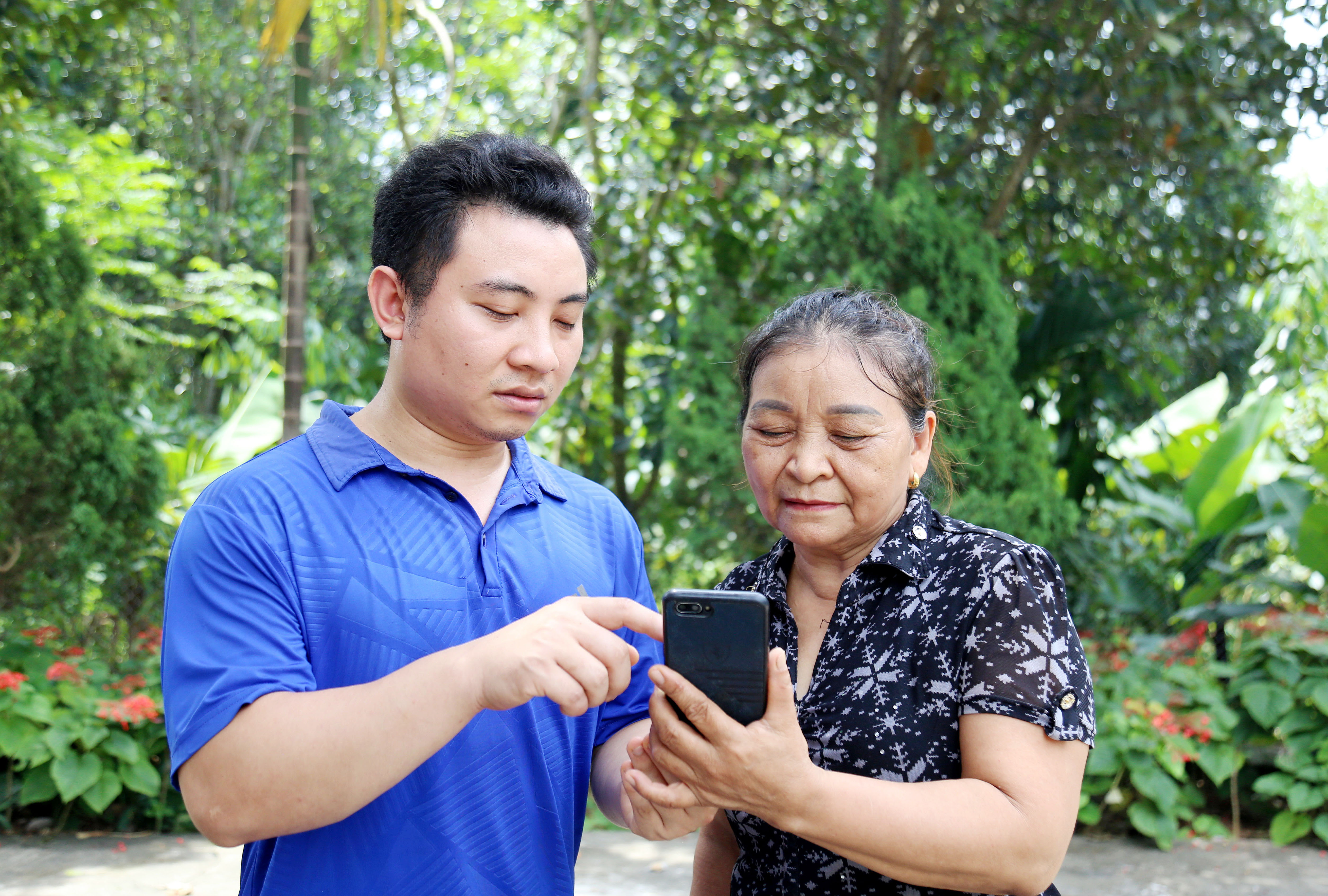Thành viên Tổ Công nghệ số cộng đồng thôn Tả Hà hướng dẫn người cao tuổi thực hiện các bước đăng ký thủ tục hành chính trên điện thoại thông minh.